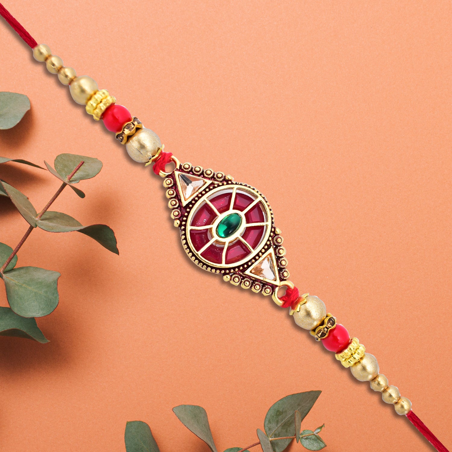 Royal Designer Rakhi With Kundan Centerpiece Red  Green Enamel Work And Golden Beads Royal Designer Rakhi With Kundan Centerpiece Red  Green Enamel Work And Golden Beads